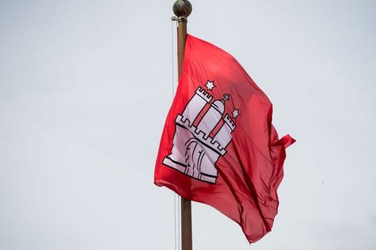 Die Fahne mit dem Wappen Hamburgs vor dem Rathaus der Hansestadt.