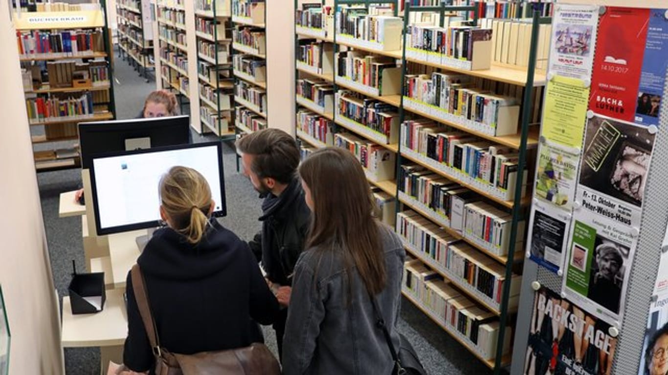 Besucher einer Stadtbibliothek informieren sich an einem Computer.