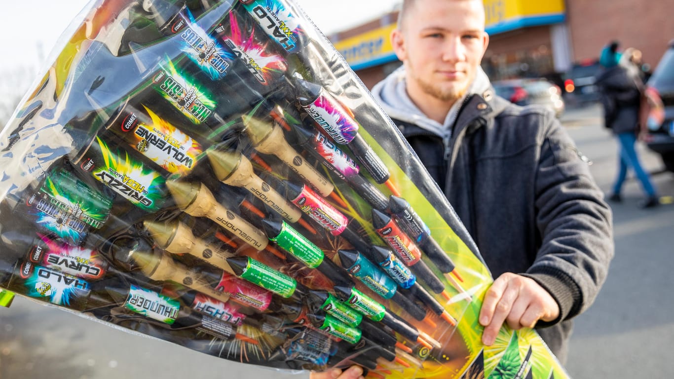 Ein Mann steht mit einer Packung Feuerwerksartikeln auf dem Parkplatz eines Einkaufszentrums: Vom 28.12. bis zum 31.12. dürfen Geschäfte Feuerwerksartikel verkaufen.