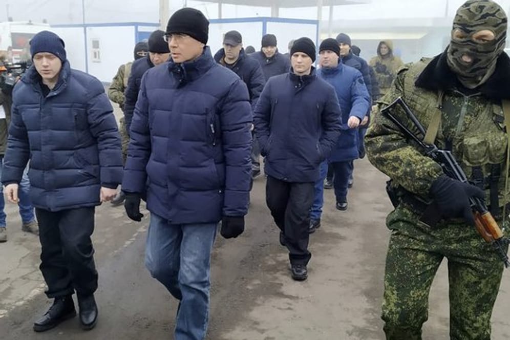Ein Separatistensoldat begleitet ukrainische Kriegsgefangene zum Kontrollpunkt.