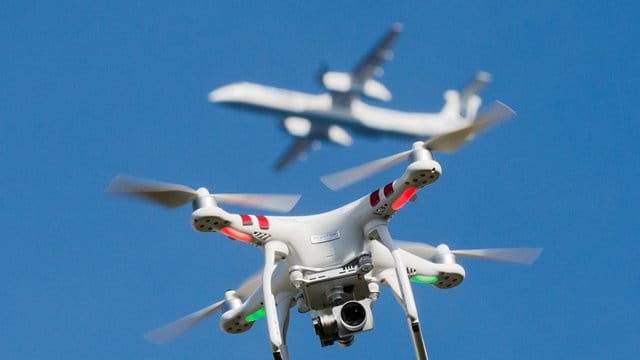 Eine private Drohne fliegt in knapp 10 Metern Flughöhe über einem Garten, in weiter Entfernung ist ein Flugzeug beim Anflug auf den Flughafen Düsseldorf zu sehen ist. Eine private Drohne fliegt in knapp 10 Metern Flughöhe über einem Garten, in weiter Entfernung ist ein Flugzeug beim Anflug auf den Flughafen Düsseldorf zu sehen ist.