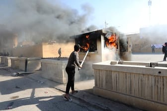 Ein Demonstrant schürt vor der Botschaft der Vereinigten Staaten in Bagdad ein Feuer.
