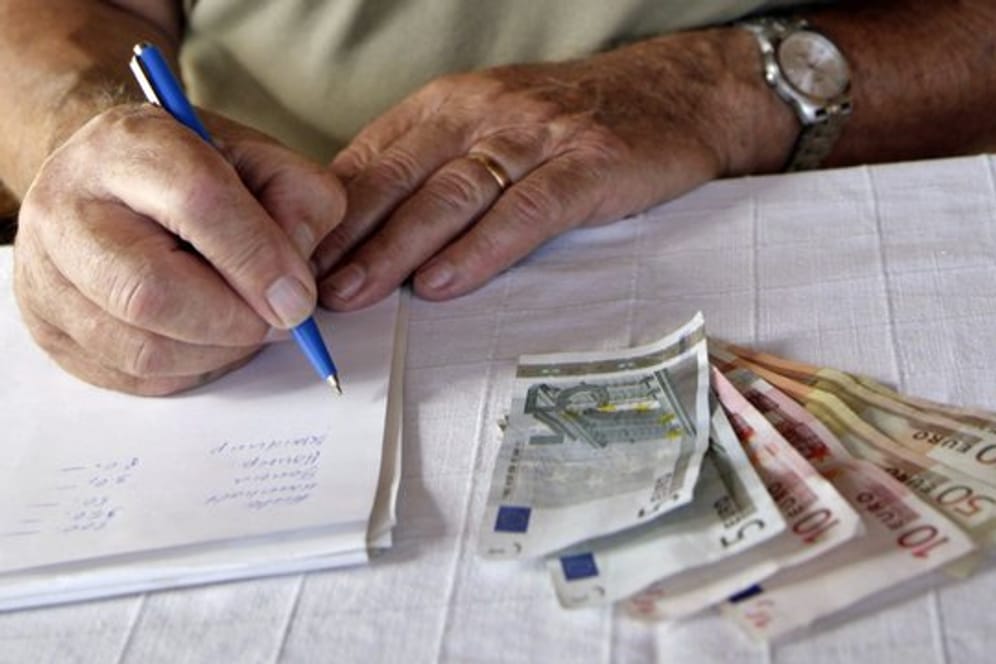 Ein Rentner macht sich auf einem Block diverse Notizen seiner Geldausgaben.