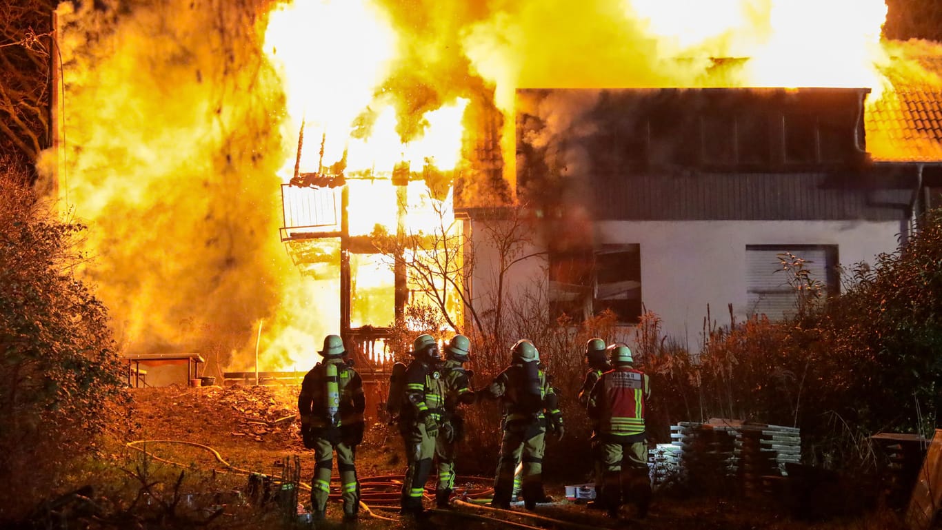 Nordrhein-Westfalen, Solingen: Mitglieder der Feuerwehr stehen vor dem brennenden Zweifamilienhaus, das komplett ausbrannte.