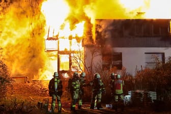 Nordrhein-Westfalen, Solingen: Mitglieder der Feuerwehr stehen vor dem brennenden Zweifamilienhaus, das komplett ausbrannte.