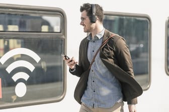 Mann vor Wlan-Symbol: Bislang bietet die Deutsche Bahn kostenloses Internet flächendeckend nur in ihren Fernverkehrszügen an.