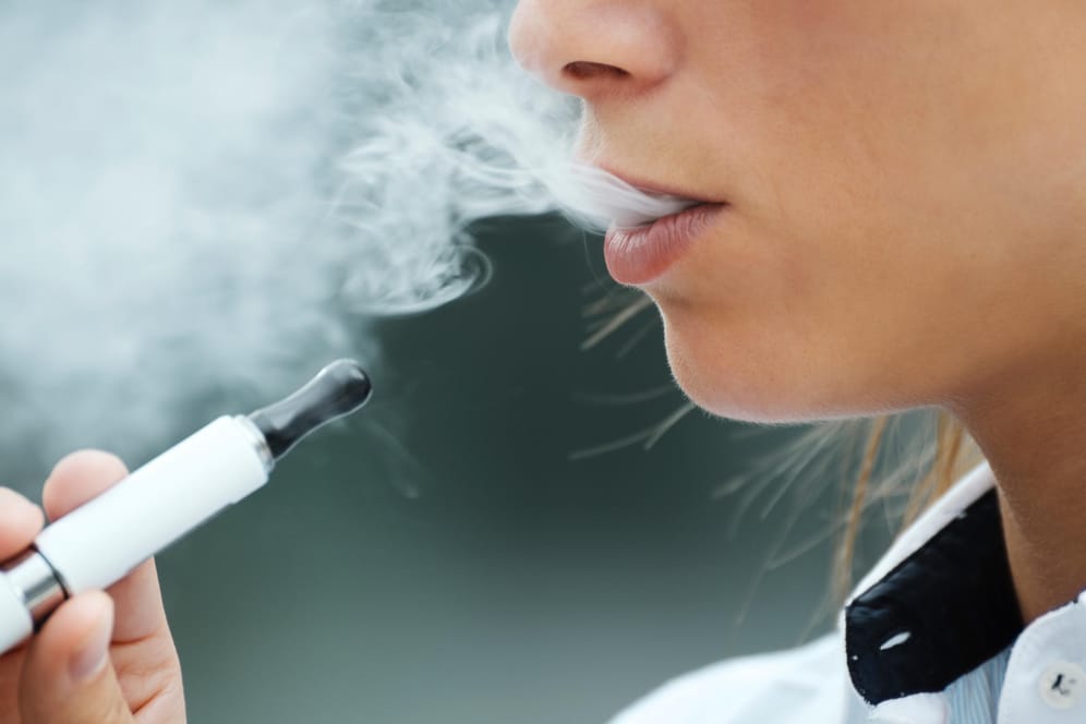 Frau raucht: In Deutschland ist die Zusammensetzung der Wirkstoffe von E-Zigaretten strenger reguliert als in den USA.