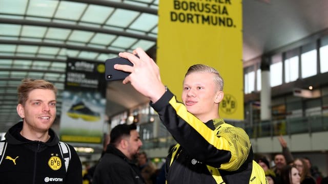 Erling Haaland (r) macht am Dortmunder Flughafen mit seinem Handy ein Selfie von sich.