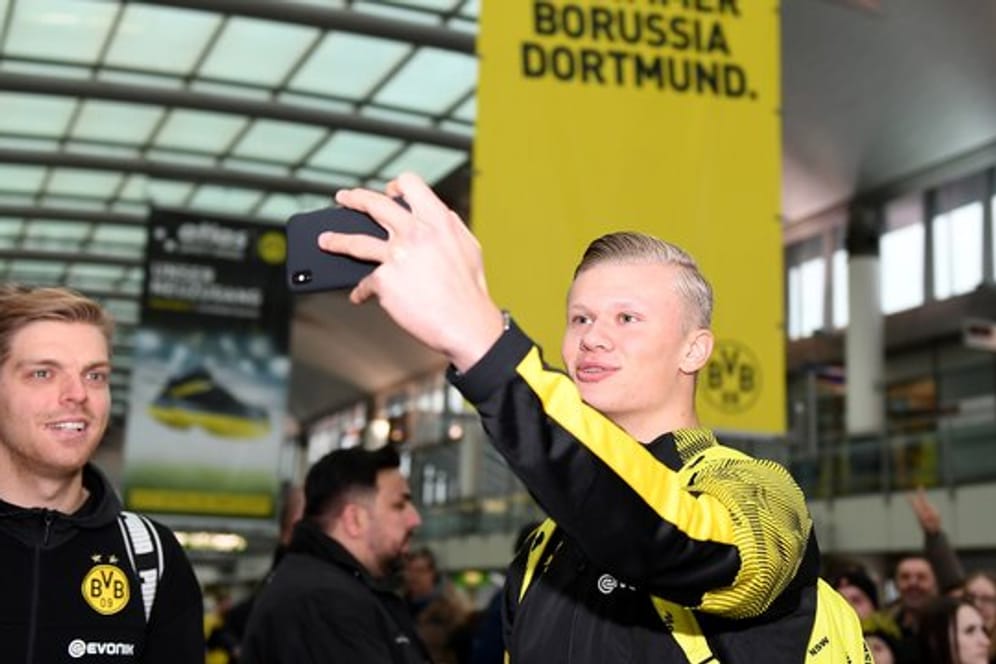 Erling Haaland (r) macht am Dortmunder Flughafen mit seinem Handy ein Selfie von sich.