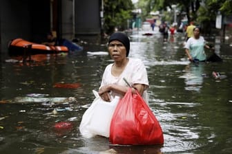 Eine Frau geht durch das Hochwasser einer überfluteten Straße in Jakarta.