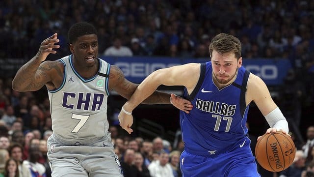 Dwayne Bacon (7/l) von den Charlotte Hornets attackiert Mavs-Spieler Luka Doncic (77).