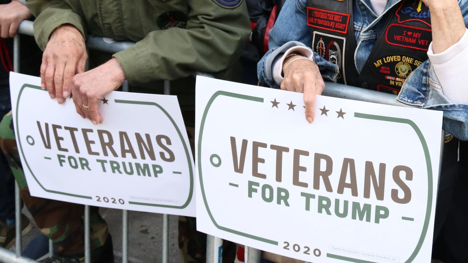 Zuschauer einer Parade halten Schilder: "Veteranen für Trump"