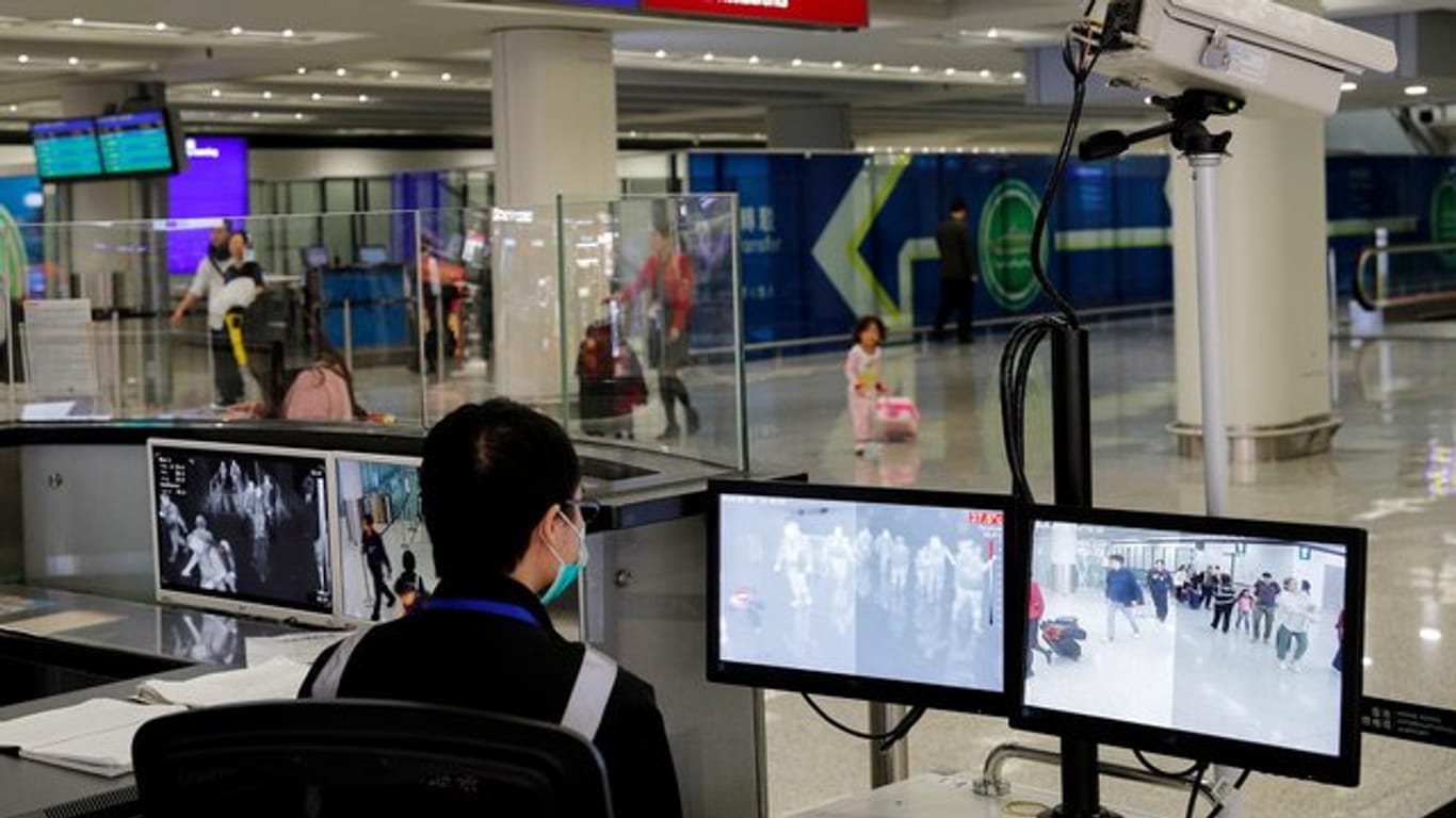 Ein Beamter der Gesundheitsüberwachung überwacht mit Wärmebildkameras die Temperatur von Reisenden am Flughafen von Hongkong ankommenden Reisenden.