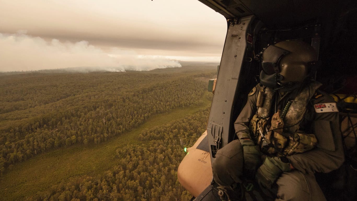 Ein Militärhubschrauber flliegt über einen Buschbrand bei Cann River: In den Bundesstaaten New South Wales und Victoria lodern noch mehr als 180 Feuer.