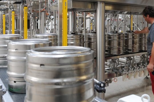 Bierfässer in einer Abfüllanlage: Die Radeberger Gruppe hebt für den Großteil seiner Produkte den Preis an.