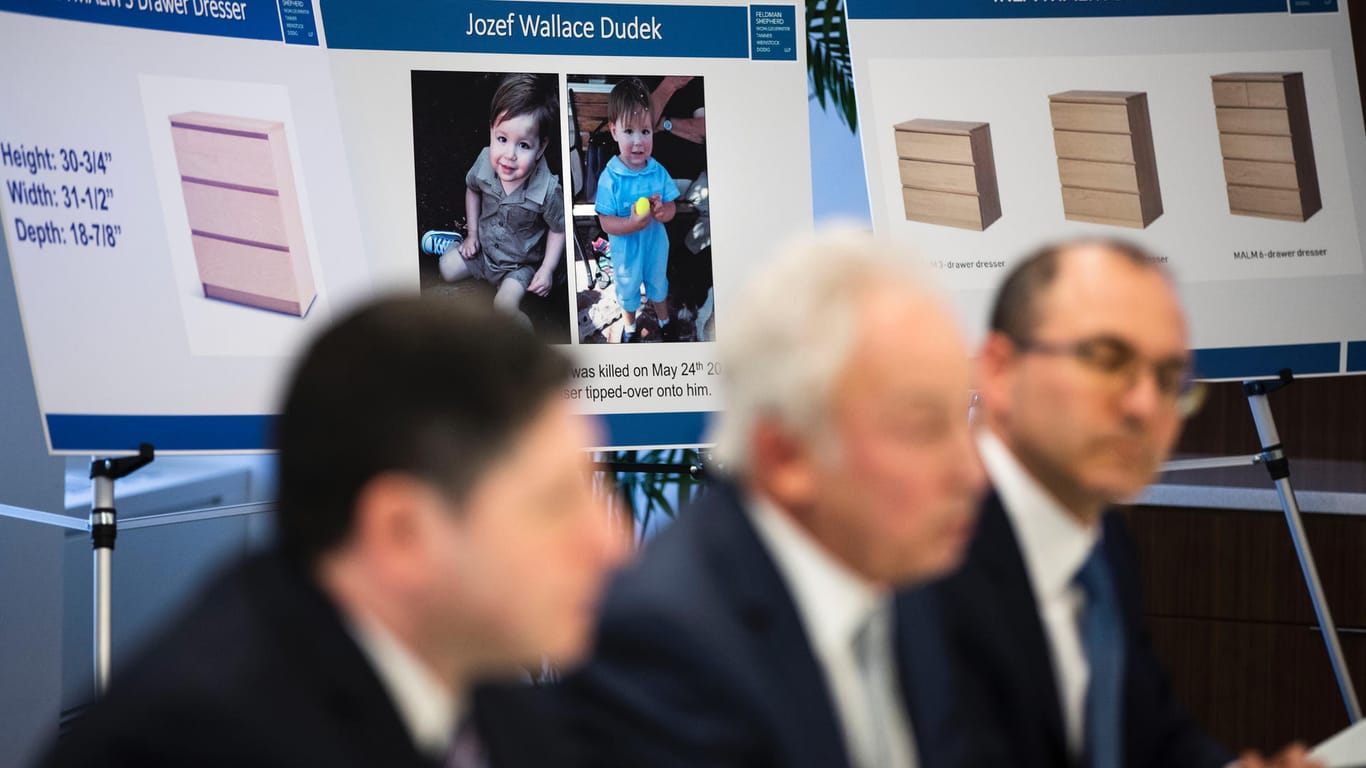Anwälte der Angeklagten sitzen vor Bildern des getöteten Kindes und der Kommode: Angeblich soll die Familie 46 Millionen Euro von dem Konzern erhalten.