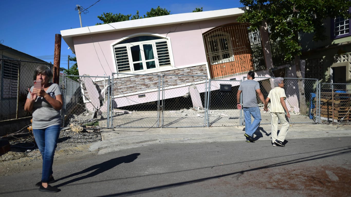 Anwohner betrachten ein Haus, das nach einem Erdbeben in Guanica teilweise eingestürzt ist: Behörden ließen die Küste der Insel vorsorglich evakuieren.