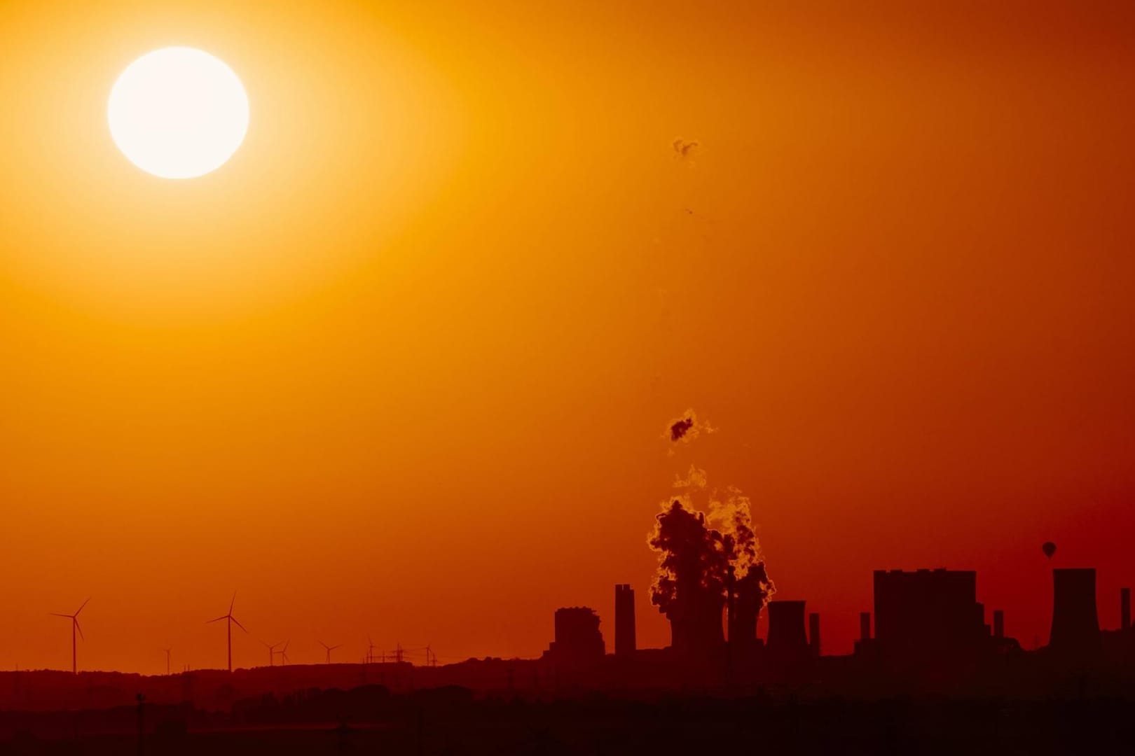 Ein deutsches Braunkohlekraftwerk und Windkraftanlagen am Horizont: Die Frage der Energiegewinnung ist entscheidend für die Zukunft des Erdklimas. (Symbolbild)