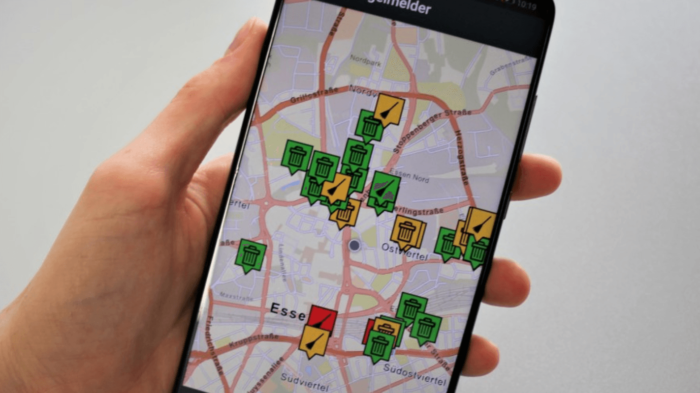 Eine Hand hält ein Smartphone, auf dem die Mängelmelder-App zu sehen ist: Schäden an Straßen und Wegen in Essen können so gemeldet werden.