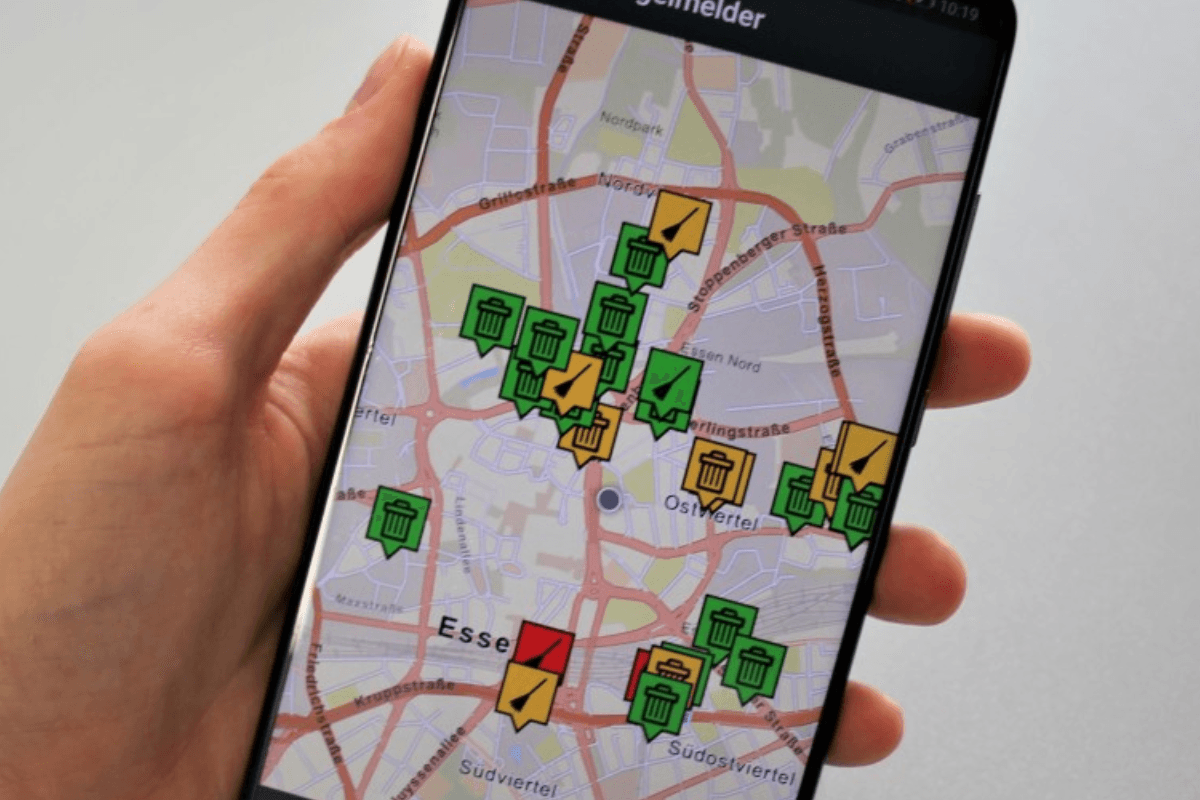 Eine Hand hält ein Smartphone, auf dem die Mängelmelder-App zu sehen ist: Schäden an Straßen und Wegen in Essen können so gemeldet werden.