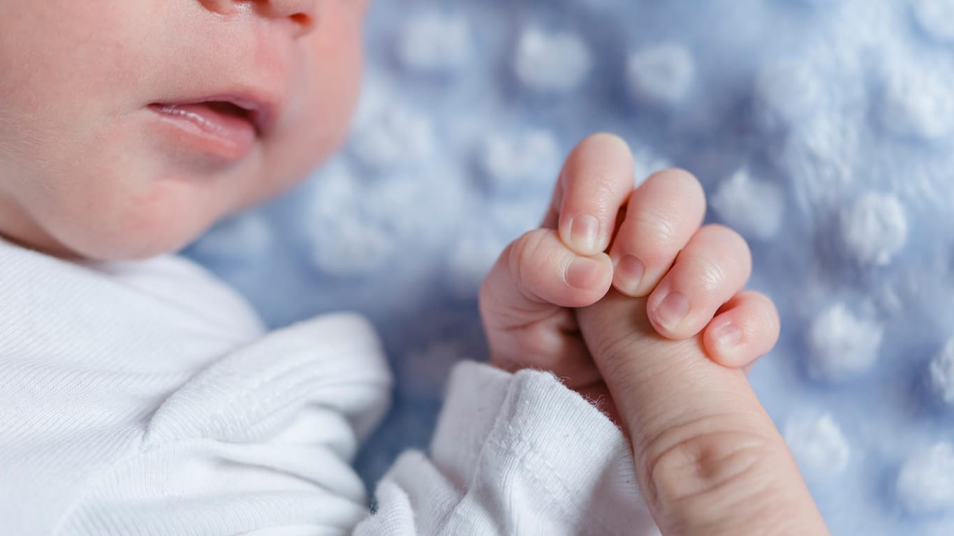 Ein Baby umklammert einen Finger (Symbolbild): In Frankfurt wählen die Eltern lieber traditionelle Vornamen.
