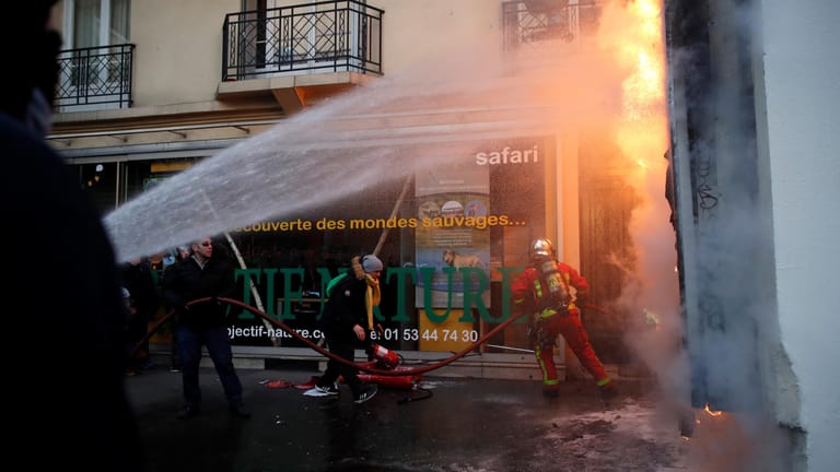 Zusammenstöße in Paris: Feuerwehrleute löschen eine Plakatwand, die von Demonstranten in Brand gesetzt wurde.