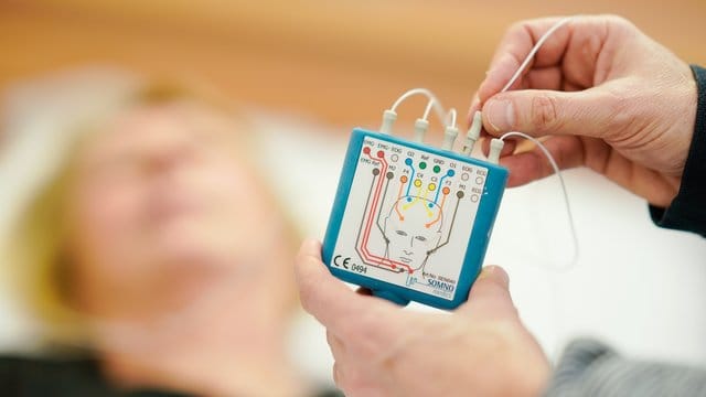 Am Kopf einer Frau befestigte Elektroden werden im Schlafzentrum an ein Schlaf-Aufzeichnungsgerät angeschlossen. Am Kopf einer Frau befestigte Elektroden werden im Schlafzentrum an ein Schlaf-Aufzeichnungsgerät angeschlossen.