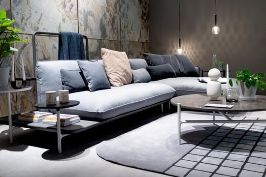 Designer nutzen eine Farbfamilie: Das kieselgraue Sofa mit integrierter Ablagefläche kombiniert der Hersteller Rolf Benz mit dunkelgrauen Kissen.