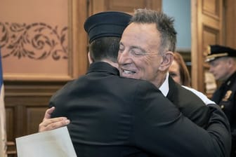 Bruce Springsteen (vorne, r), umarmt seinen Sohn Sam, nachdem dieser im Rathaus von Jersey City als Feuerwehrmann vereidigt wurde.
