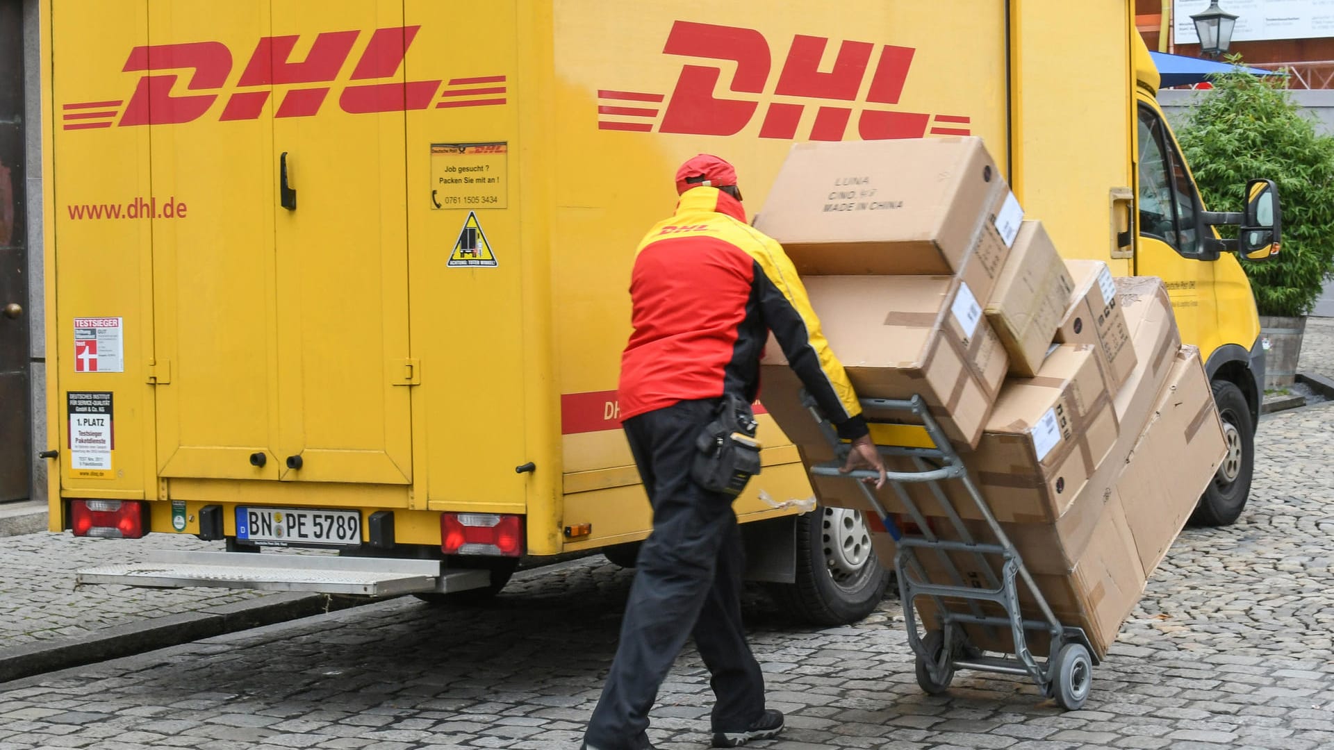 Ein DHL-Paketzusteller vor seinem Transporter: Bundesweit verschicken Betrüger SMS im Namen des Paketlieferdienstes. Ein DHL-Paketzusteller vor seinem Transporter: Bundesweit verschicken Betrüger SMS im Namen des Paketlieferdienstes.