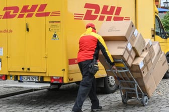 Ein DHL-Paketzusteller vor seinem Transporter: Bundesweit verschicken Betrüger SMS im Namen des Paketlieferdienstes.