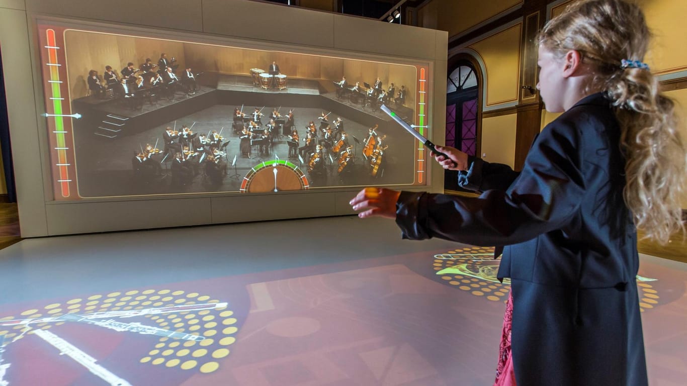 Ein Kind steht vor einem virtuellen Orchester: Im Toccarion können Kinder selbst die Welt der Musik entdecken.