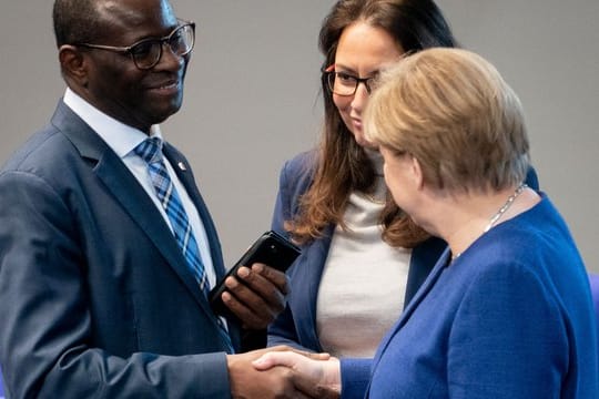 Bundeskanzlerin Angela Merkel (CDU) stellt sich hinter den SPD-Bundestagsabgeordneten Karamba Diaby (li), nachdem dessen Bürgerbüro angegriffen wurde.
