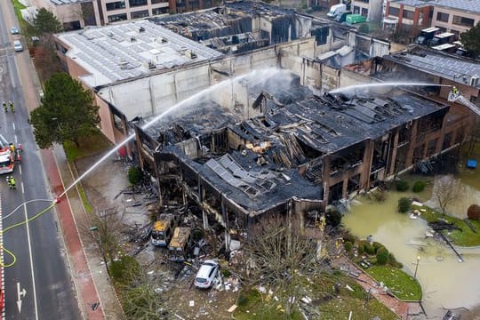 Die Feuerwehr löscht eine ausgebrannte Lagerhalle nach einem Großbrand in der Nacht.