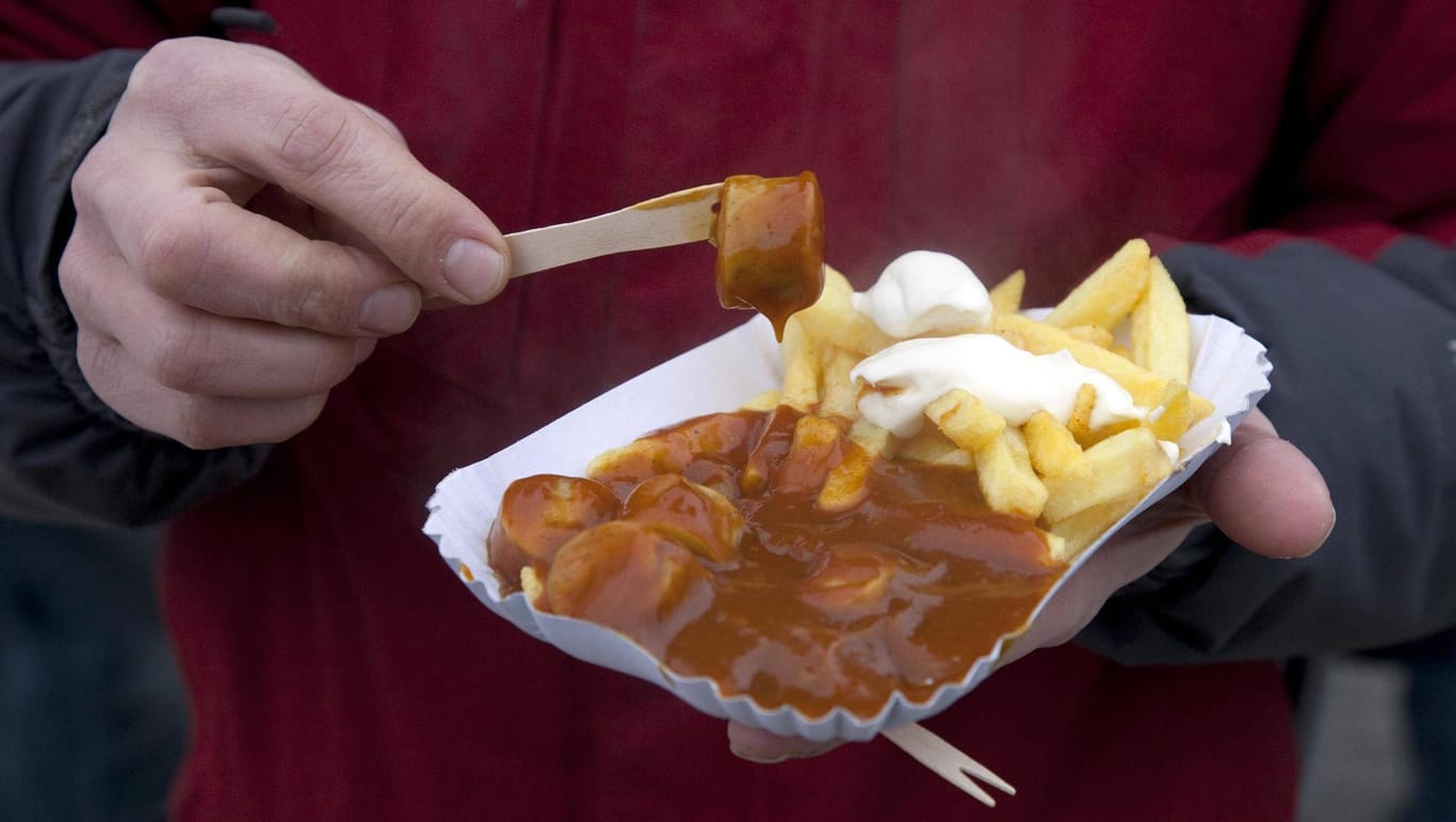 Ein Mann isst Currywurst mit Pommes: Ein Essener Gastronom will die klassische Currywurst erhalten.