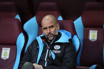 Pep Guardiola, Trainer von Manchester City, sitzt während eines Spiels auf der Trainerbank.