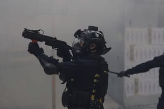 Ein Polizist zielt mit Tränengas auf Demonstranten bei regierungskritischen Protesten.