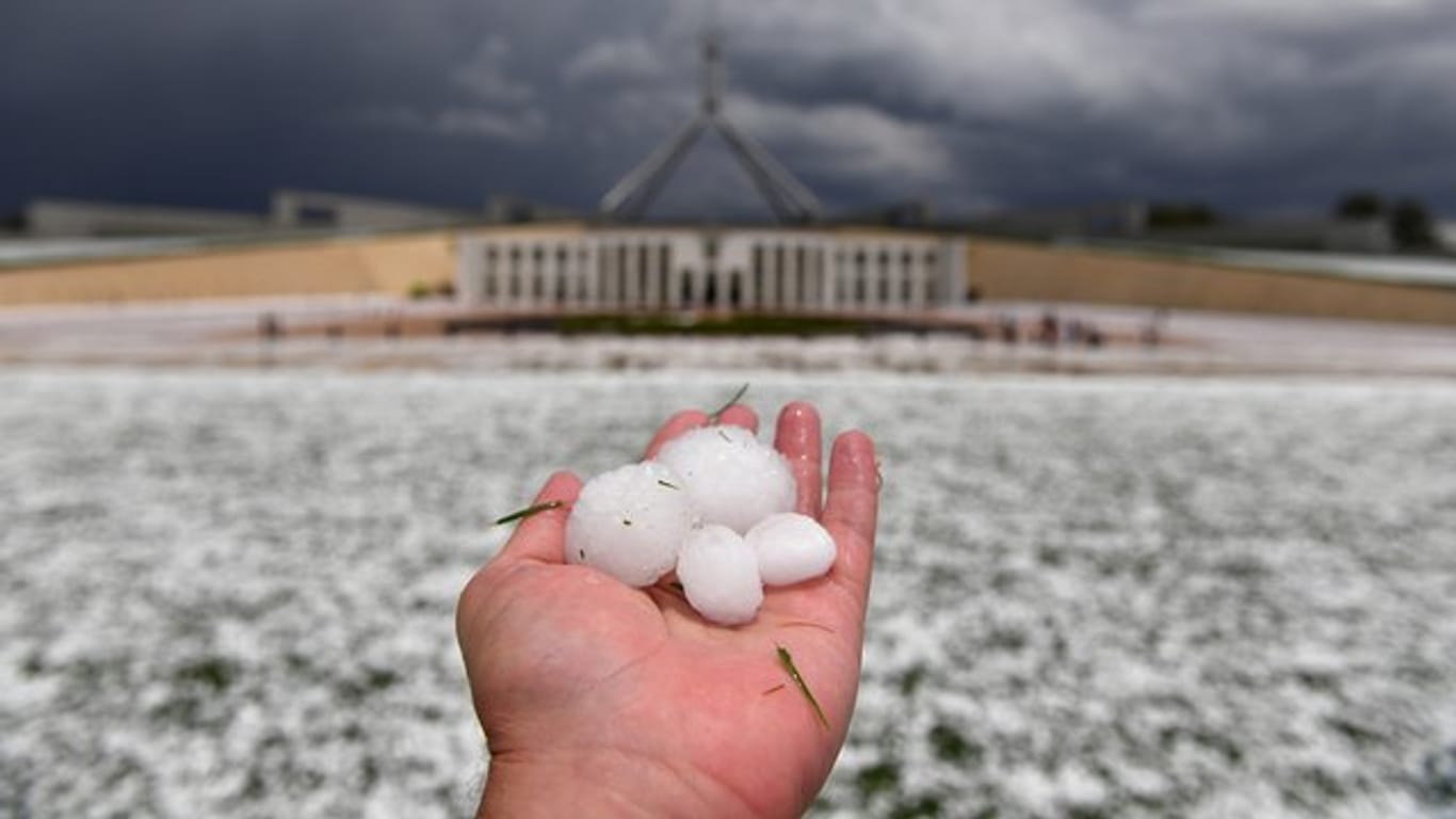 Auf einer Hand liegen Golfballgroße Hagelkörner, die bei einem schweren Hagelsturm vor dem Parlamentsgebäude niedergegangen sind.