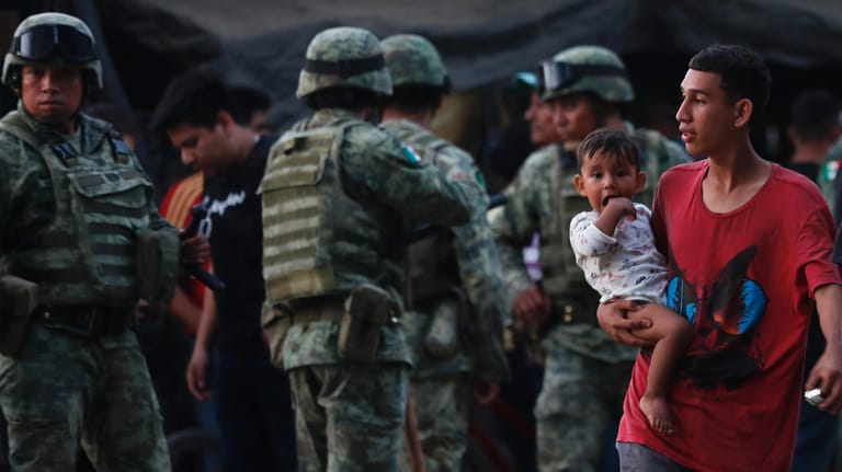 Ein Mann steht mit seinem Kind vor Kräften der mexikanischen Nationalgarde: Die Migranten stammen meist aus Mittelamerika und wollen in die USA.