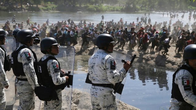 Migranten passieren mexikanischen Nationalgardisten am Grenzfluss Río Suchiate zwischen zwischen Guatemala und Mexiko. Migranten passieren mexikanischen Nationalgardisten am Grenzfluss Río Suchiate zwischen zwischen Guatemala und Mexiko.