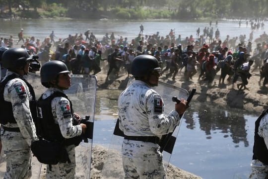 Migranten passieren mexikanischen Nationalgardisten am Grenzfluss Río Suchiate zwischen zwischen Guatemala und Mexiko.