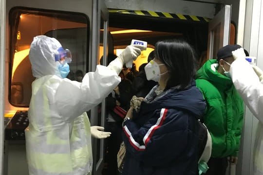 Gesundheitsbeamte kontrollieren in Peking die Körpertemperatur aus Wuhan angereister Passagiere.