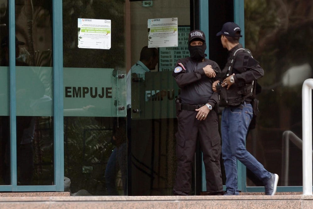 Beamte des venezolanischen Geheimdienstes Sebin betreten das Gebäude, in dem sich das Büro befindet: Guaidó befand sich während des Einsatzes auf Reisen.