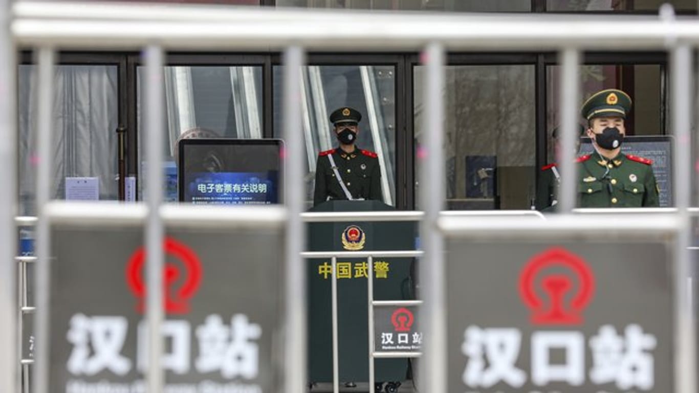 Sicherheitskräfte stehen mit Mundschutz vor dem geschlossenen Bahnhof Hankou in Wuhan.