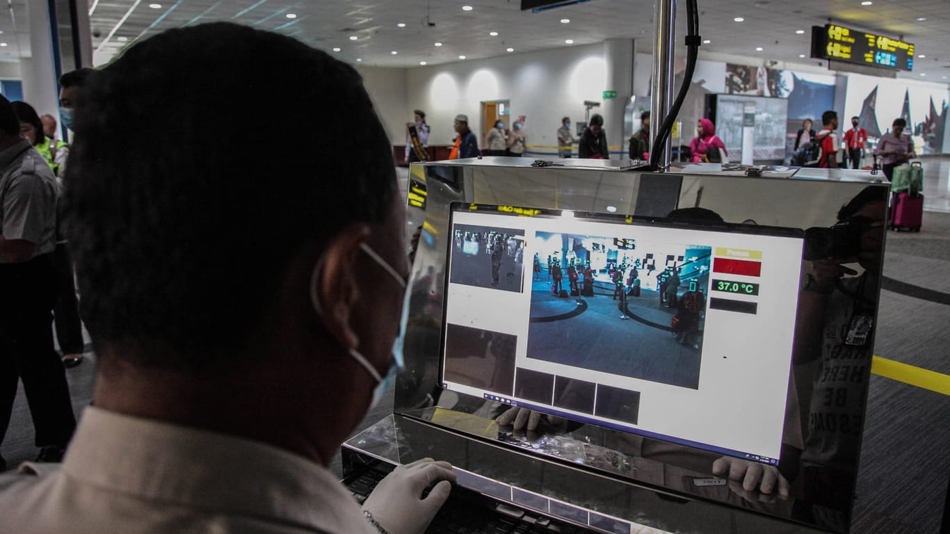 In Sumatra kontrolliert und scannt ein Flughafenmitarbeiter Passagiere aus China.