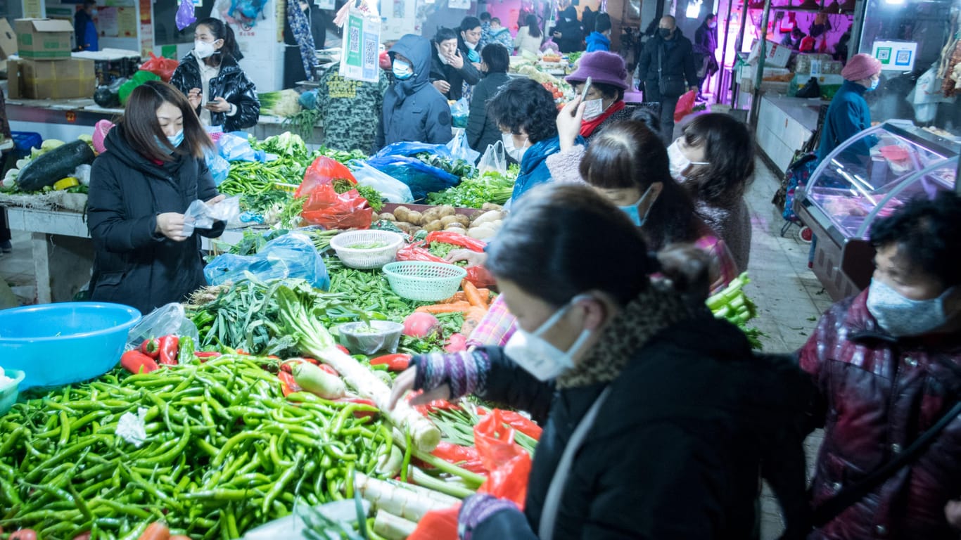 Bürger kaufen Gemüse auf einem Markt in Wuhan: Vermutlich wurde das Virus auf einem solchen Markt von einem Wildtier auf den Menschen übertragen.