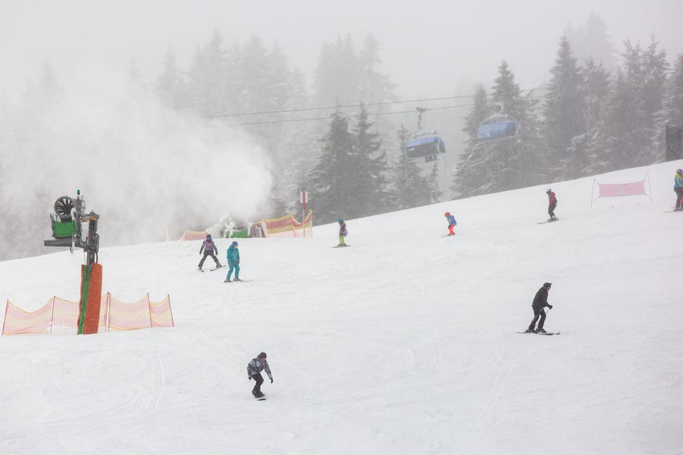 Schnee: Wintersportler fahren eine Skipiste auf dem Feldberg im Schwarzwald herunter.