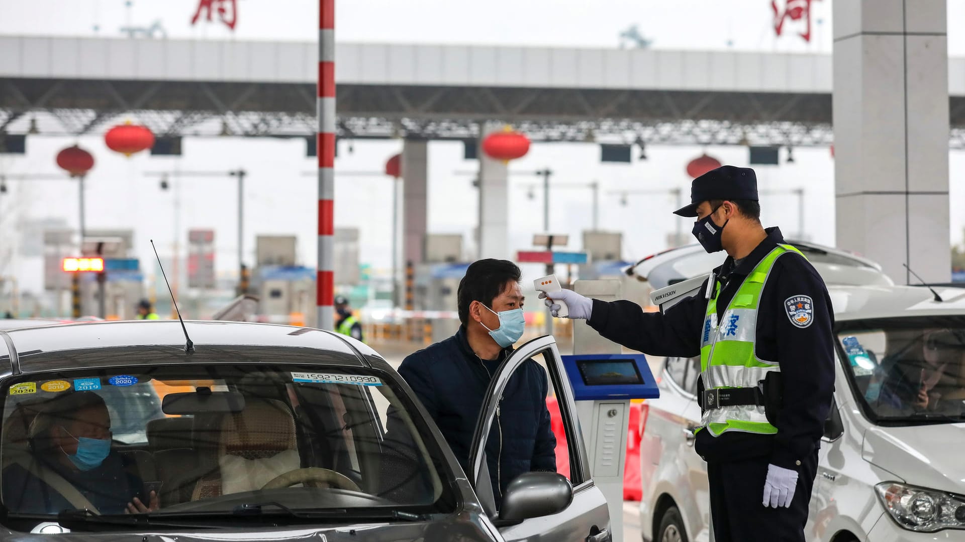 Ein Polizist testet einen Autofahrer in Wuhan auf Fieber. Menschen mit erhöhter Temperatur werden sofort in Quarantänezentren gebracht.