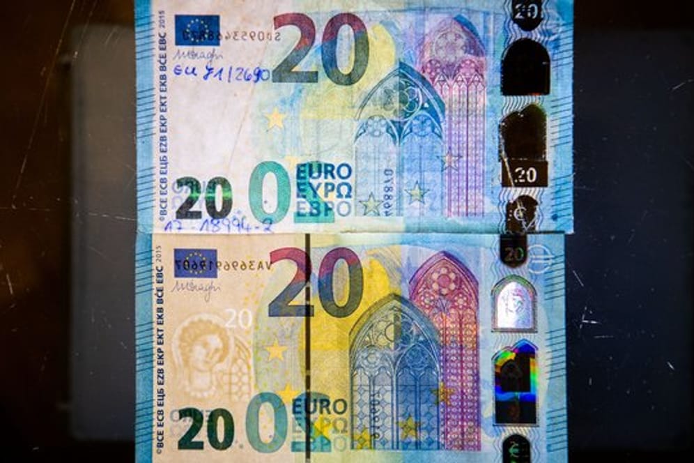 Fälschung und Original: Um einen echten Geldschein (unten) von einer nachgemachten Banknote (oben) unterscheiden zu können, sollten Bankkunden auf die Sicherheitsmerkmale achten.