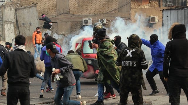 Rauch und Tränengas steigen bei Zusammenstößen zwischen Demonstranten und Sicherheitskräften in Bagdad auf. Rauch und Tränengas steigen bei Zusammenstößen zwischen Demonstranten und Sicherheitskräften in Bagdad auf.